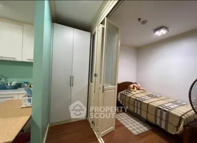 Cozy bedroom with single bed, wardrobe, and folding doors in modern apartment.