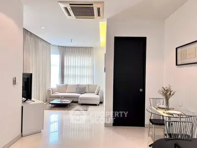 Elegant and modern living room with glossy white floor tiles, plush sofa set, and chic dining area, bathed in natural light from the sheer curtains.