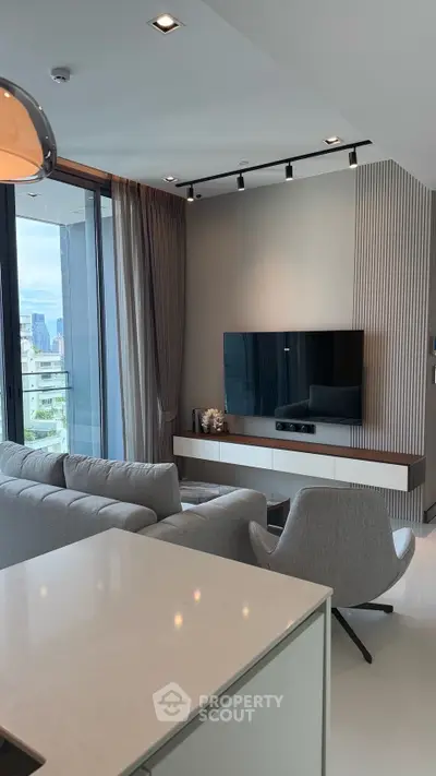 Modern living room with sleek design, featuring a large TV, comfortable seating, and a view of the city skyline.