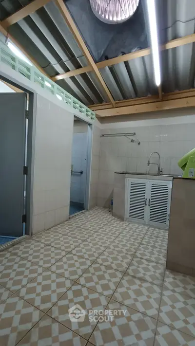 Spacious tiled kitchen with modern sink and open ceiling design