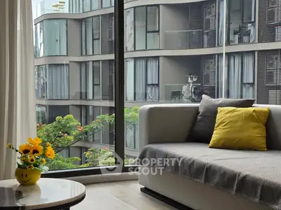Modern living room with large window offering stunning urban view and cozy seating area.
