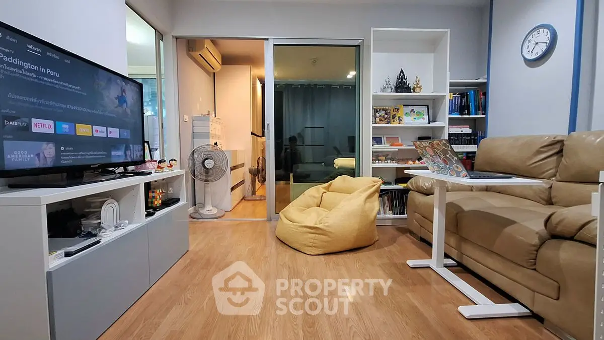 Cozy living room with modern decor, featuring a beige sofa, TV, and a bean bag chair.