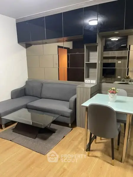 Modern living room with sleek gray sofa and glass coffee table, perfect for urban living.