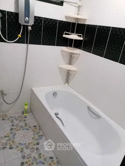 Modern bathroom with bathtub and shower, featuring stylish black and white tiles.