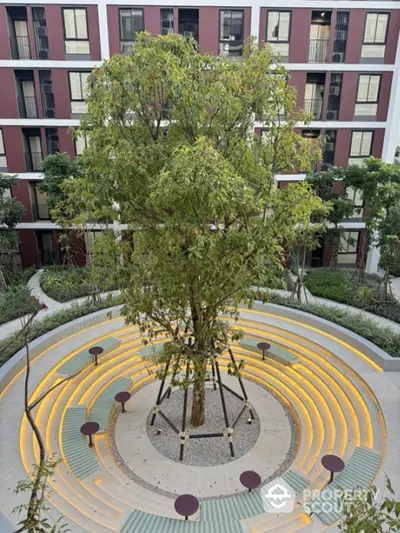 Modern apartment building with unique circular courtyard and central tree feature.