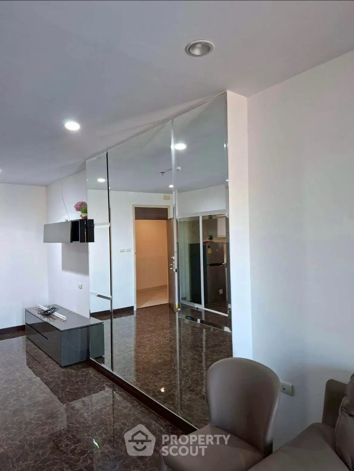 Modern living room with sleek design and mirrored wall, featuring elegant marble flooring and contemporary furniture.