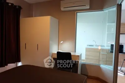 Modern bedroom with study area and view into sleek kitchen
