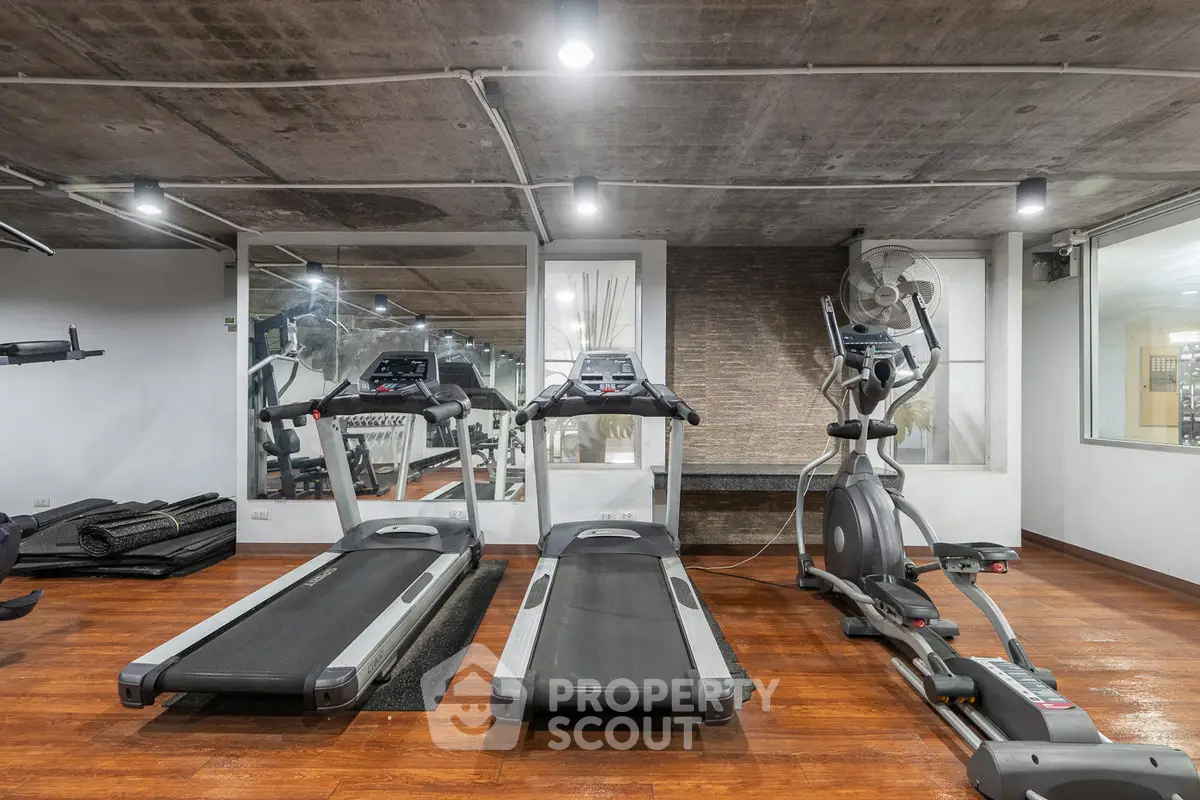 Modern gym with treadmills and exercise equipment in luxury real estate property.