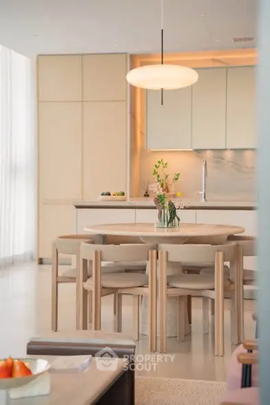 Modern kitchen with open layout and elegant dining area, featuring sleek cabinetry and contemporary lighting.