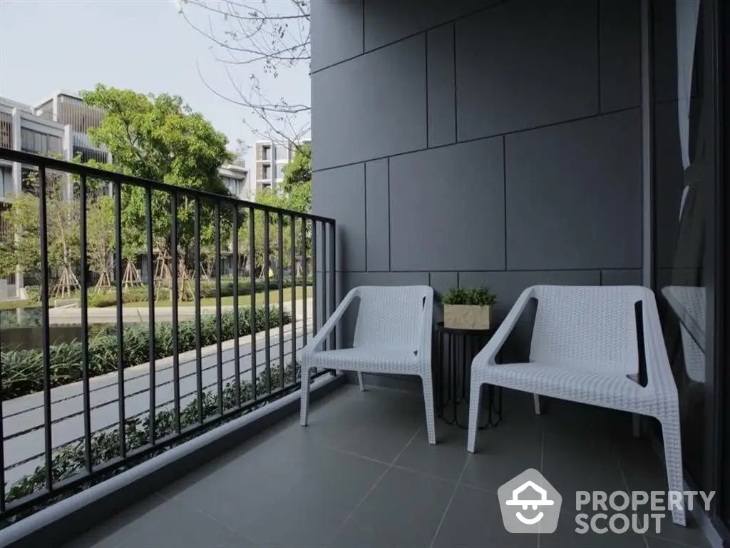 Spacious balcony with modern white loungers overlooking a serene garden, ideal for relaxation and outdoor living in a contemporary residence.