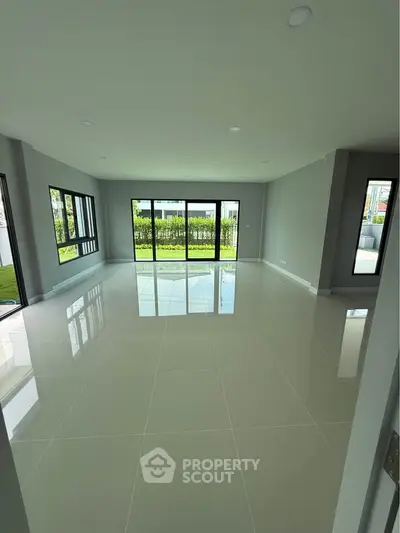 Spacious modern living room with large windows and glossy tile flooring.