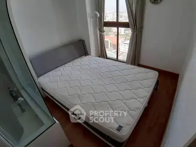 Cozy bedroom with large window offering city views, featuring a comfortable bed and modern decor.