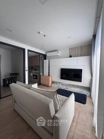 Modern living room with sleek design and natural light, featuring a cozy sofa and wall-mounted TV.