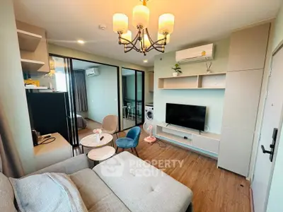 Modern living room with stylish decor and open layout, featuring a cozy sofa and flat-screen TV.