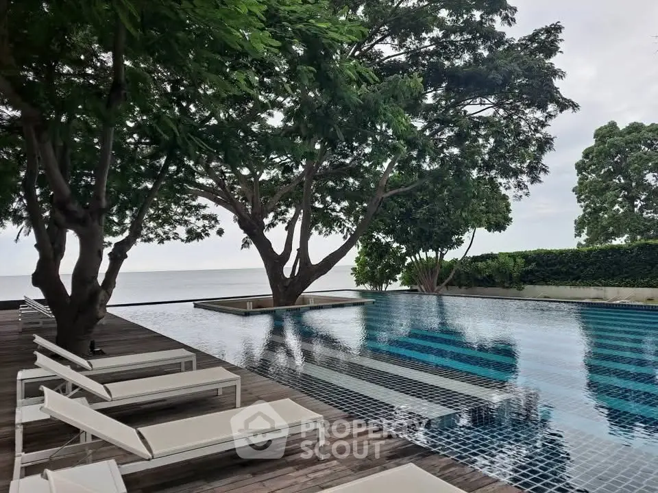 Luxurious outdoor pool area with serene ocean view and modern lounge chairs.
