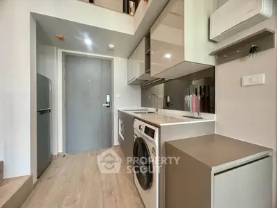 Modern kitchen with washing machine and sleek cabinetry in compact apartment