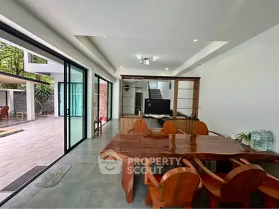 Spacious open-plan living area with wooden dining set and large sliding glass doors to patio.