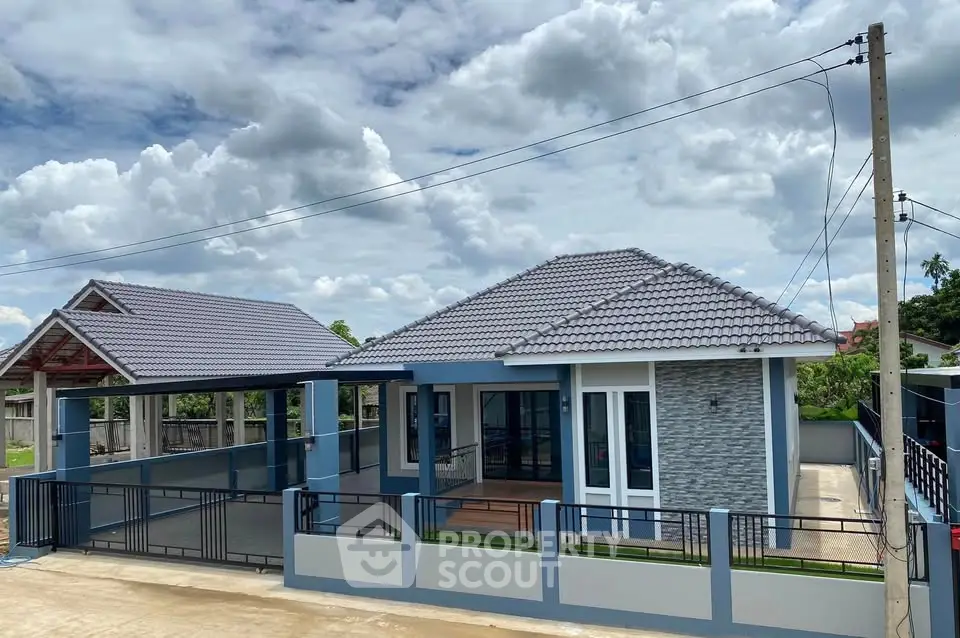 Charming modern single-story house with tiled roof and spacious driveway under a blue sky.