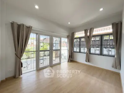 Spacious and bright living room with large windows and elegant curtains, perfect for natural light lovers.