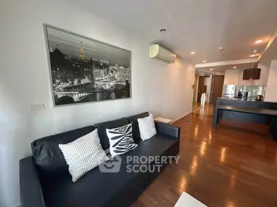 Spacious modern living room with sleek black sofa and stylish decor in open layout apartment.