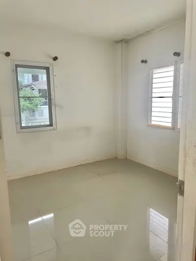 Bright empty room with tiled floor and two windows, ideal for customization.