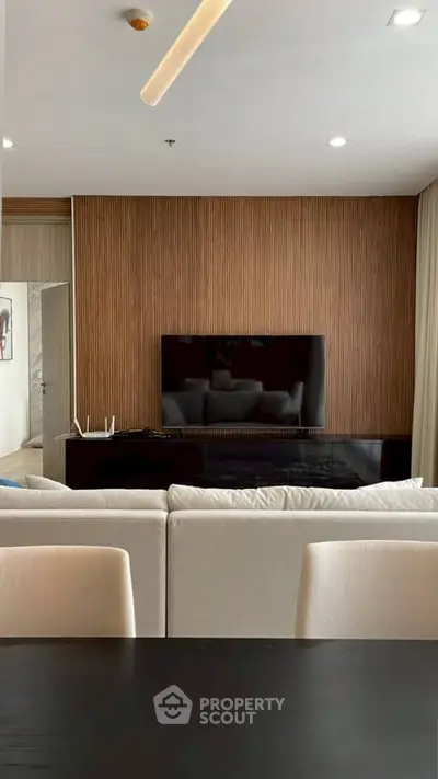 Modern living room with sleek TV setup and stylish wooden accent wall.