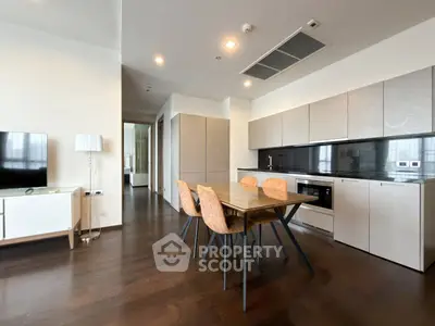 Modern open-layout kitchen and dining area with sleek cabinetry and hardwood floors.