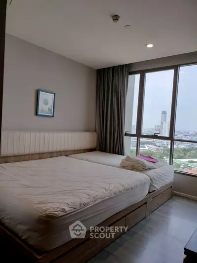 Spacious bedroom with large windows offering stunning city views, featuring two comfortable beds and modern decor.