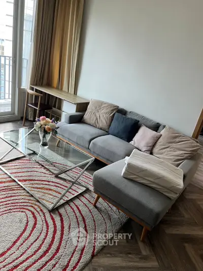 Modern living room with stylish gray sofa and glass coffee table