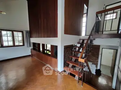 Spacious two-story living area with wooden accents and staircase, perfect for modern living.