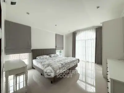 Spacious and bright bedroom with modern decor and large windows.