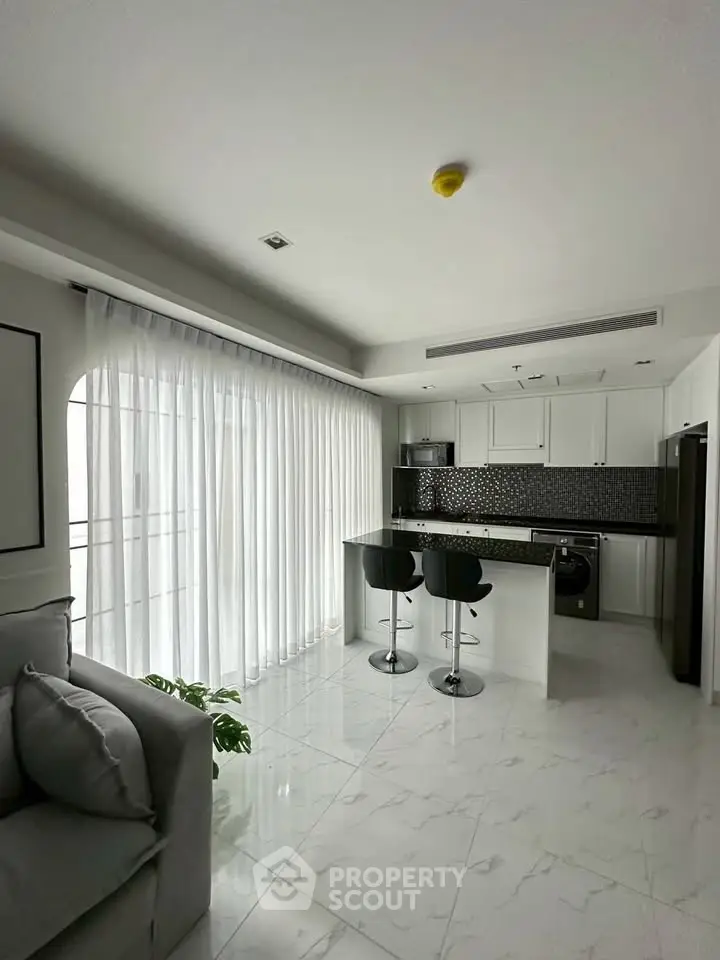 Modern open-layout kitchen with sleek design and breakfast bar in a bright apartment.