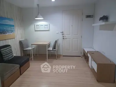 Cozy living room with modern decor and wooden flooring, featuring a small dining area and stylish lighting.