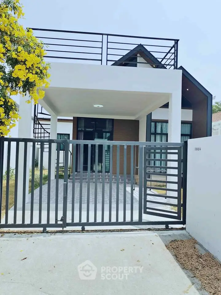 Modern two-story house with sleek design and gated entrance, featuring a spacious driveway.