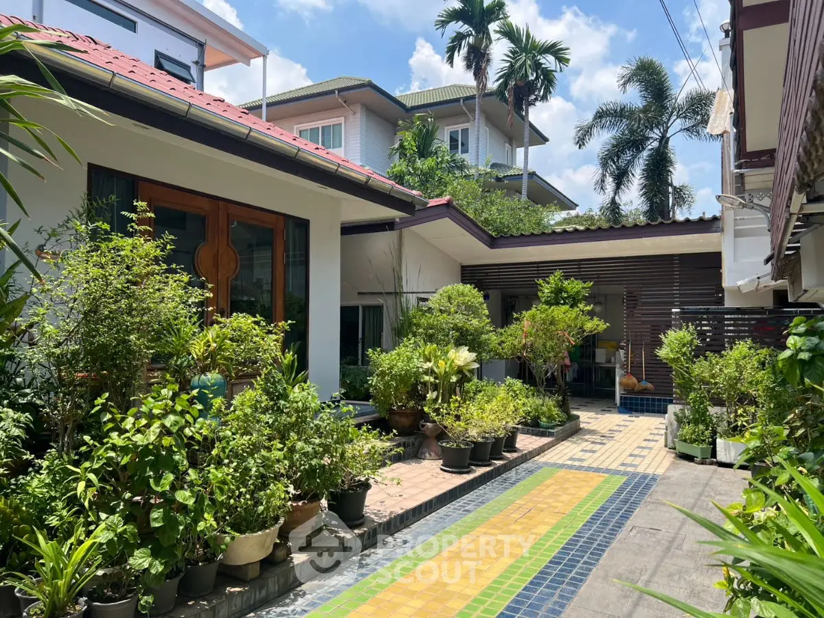 Charming garden view of a modern house with lush greenery and vibrant tiled pathway.