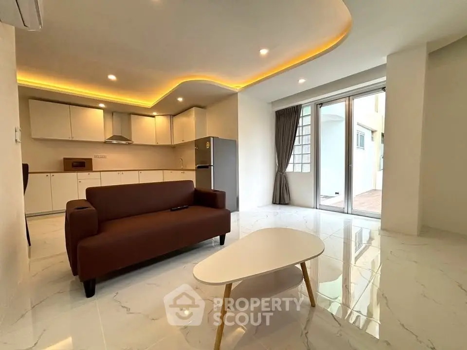 Modern open-layout living room with sleek kitchen and stylish lighting