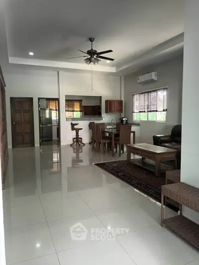 Spacious open-plan living and dining area with modern furnishings and ceiling fan.