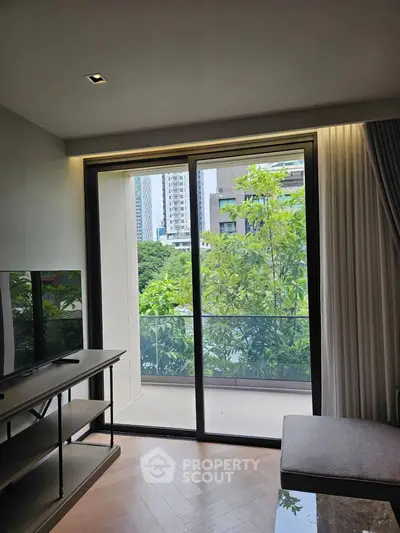 Modern living room with large glass doors opening to a lush balcony view in urban setting.