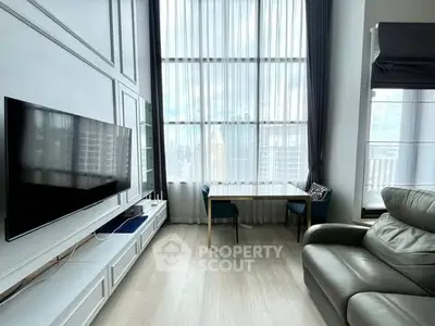 Modern living room with high ceilings, large windows, and sleek furniture.