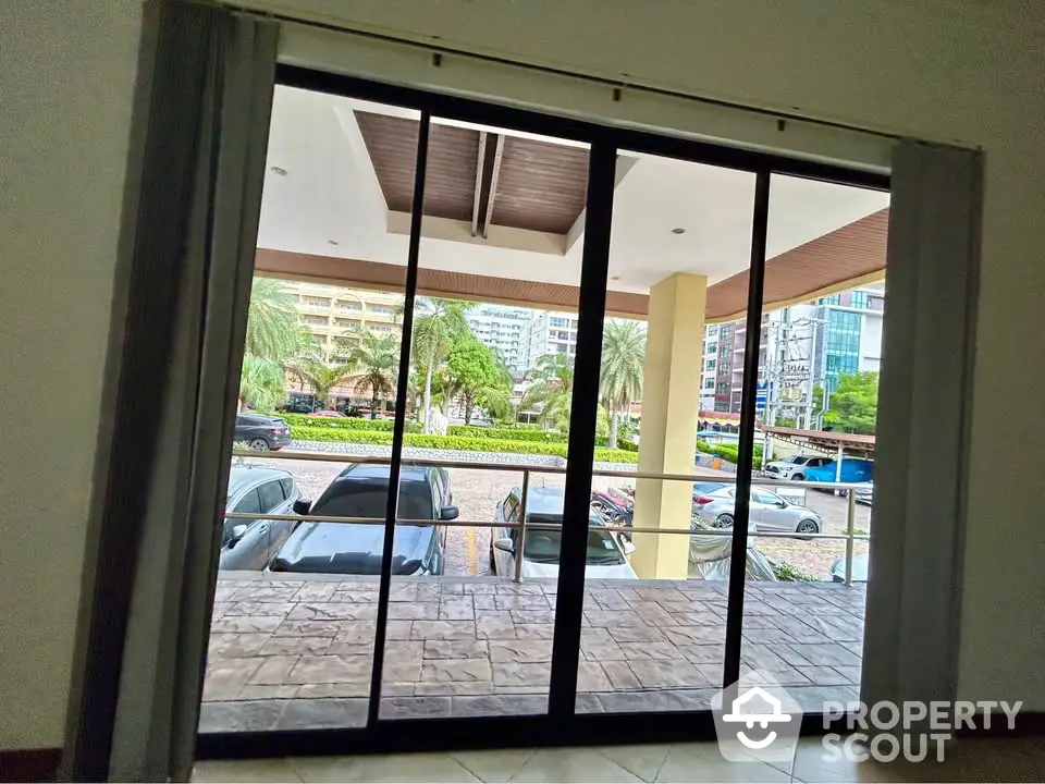 Spacious balcony view with sliding glass doors overlooking urban landscape and parked cars.