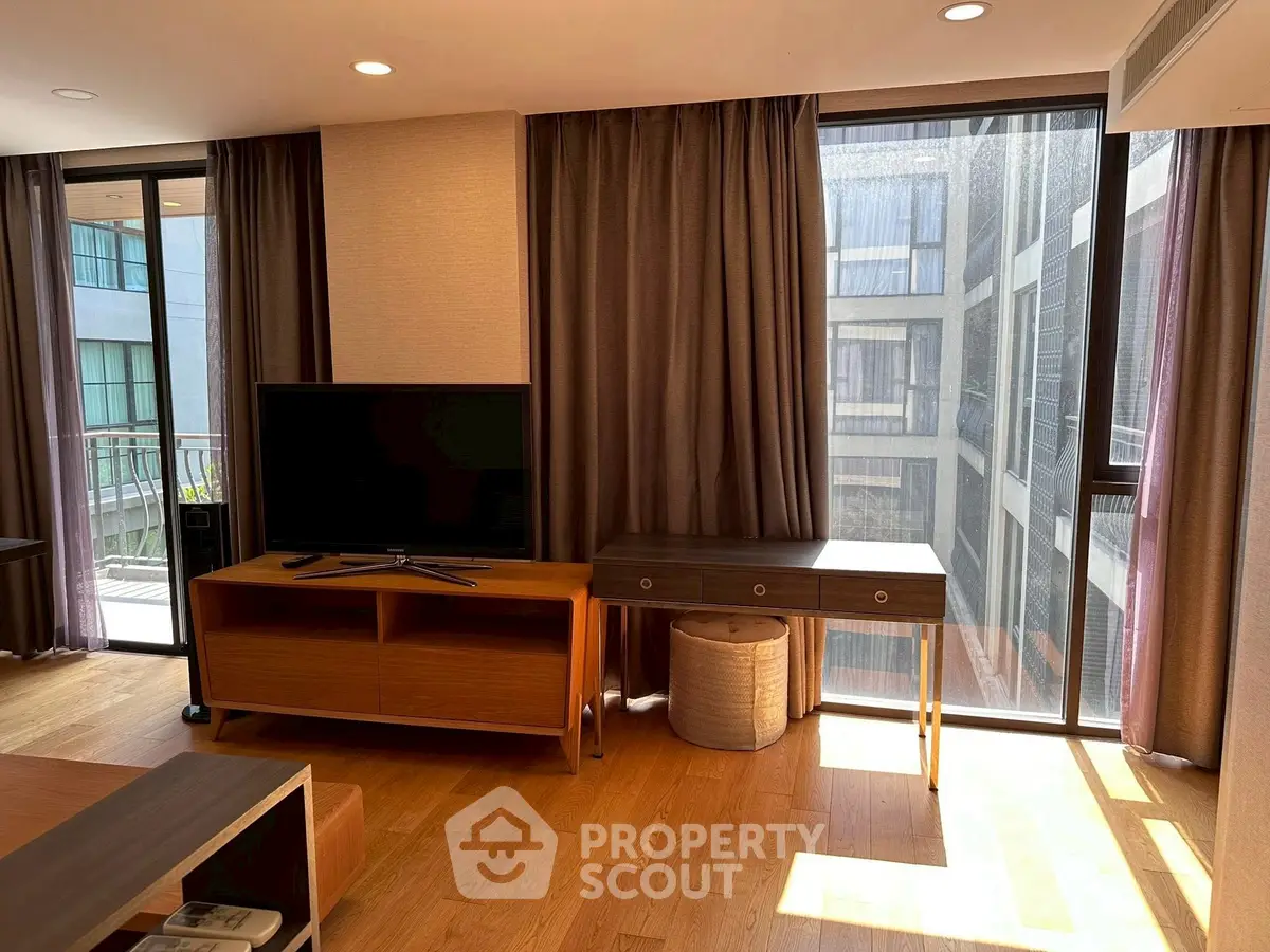 Modern living room with large windows and stylish furniture in a high-rise apartment.