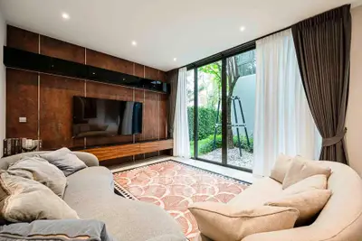 Luxurious living room with modern decor and garden view, featuring plush sofas and large TV.