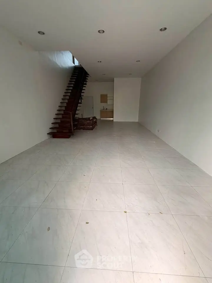 Spacious open-plan living area with modern staircase and sleek tile flooring