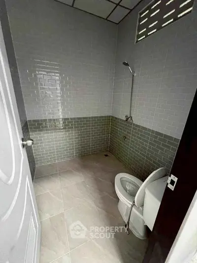Modern bathroom with tiled walls and floor, featuring a shower and toilet.