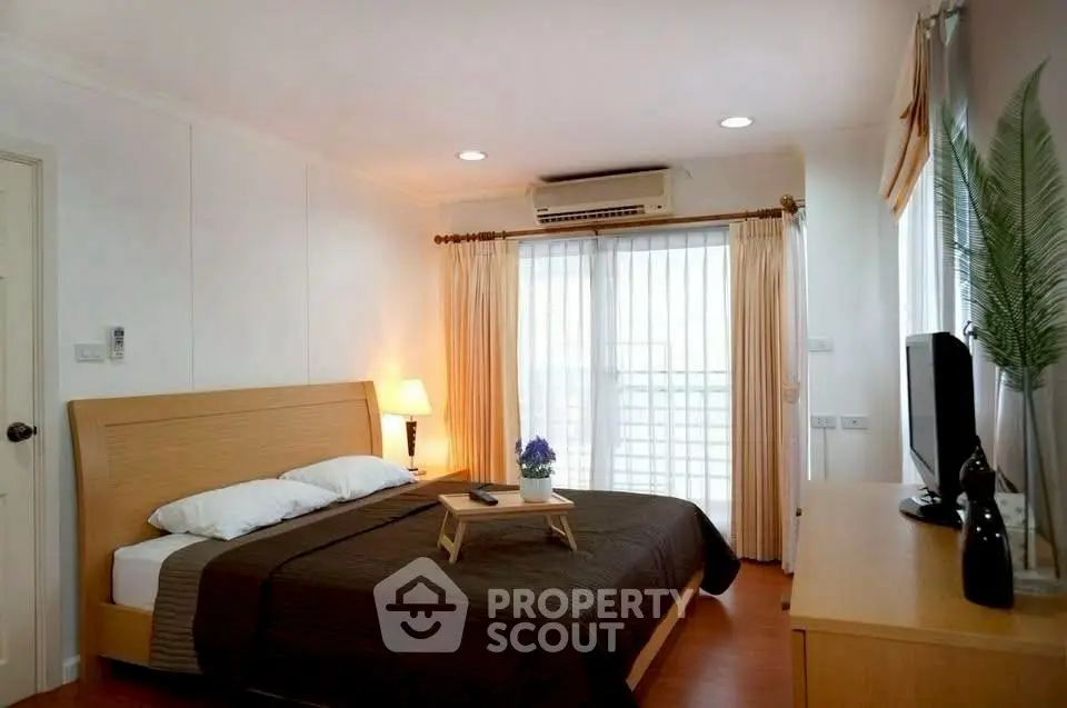 Cozy bedroom with modern decor and natural light from large windows.