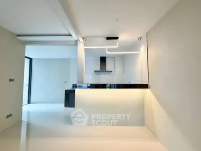 Modern kitchen with sleek design and open layout, featuring contemporary lighting and glossy tiles.