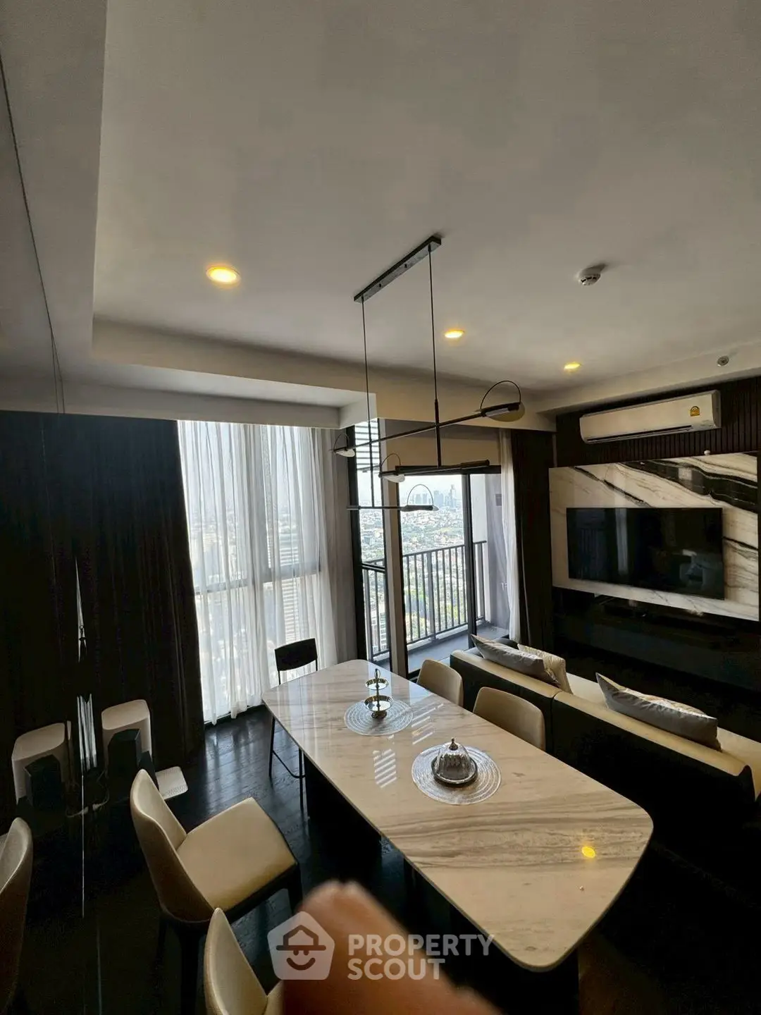 Luxurious living room with modern decor and stunning city view from balcony.