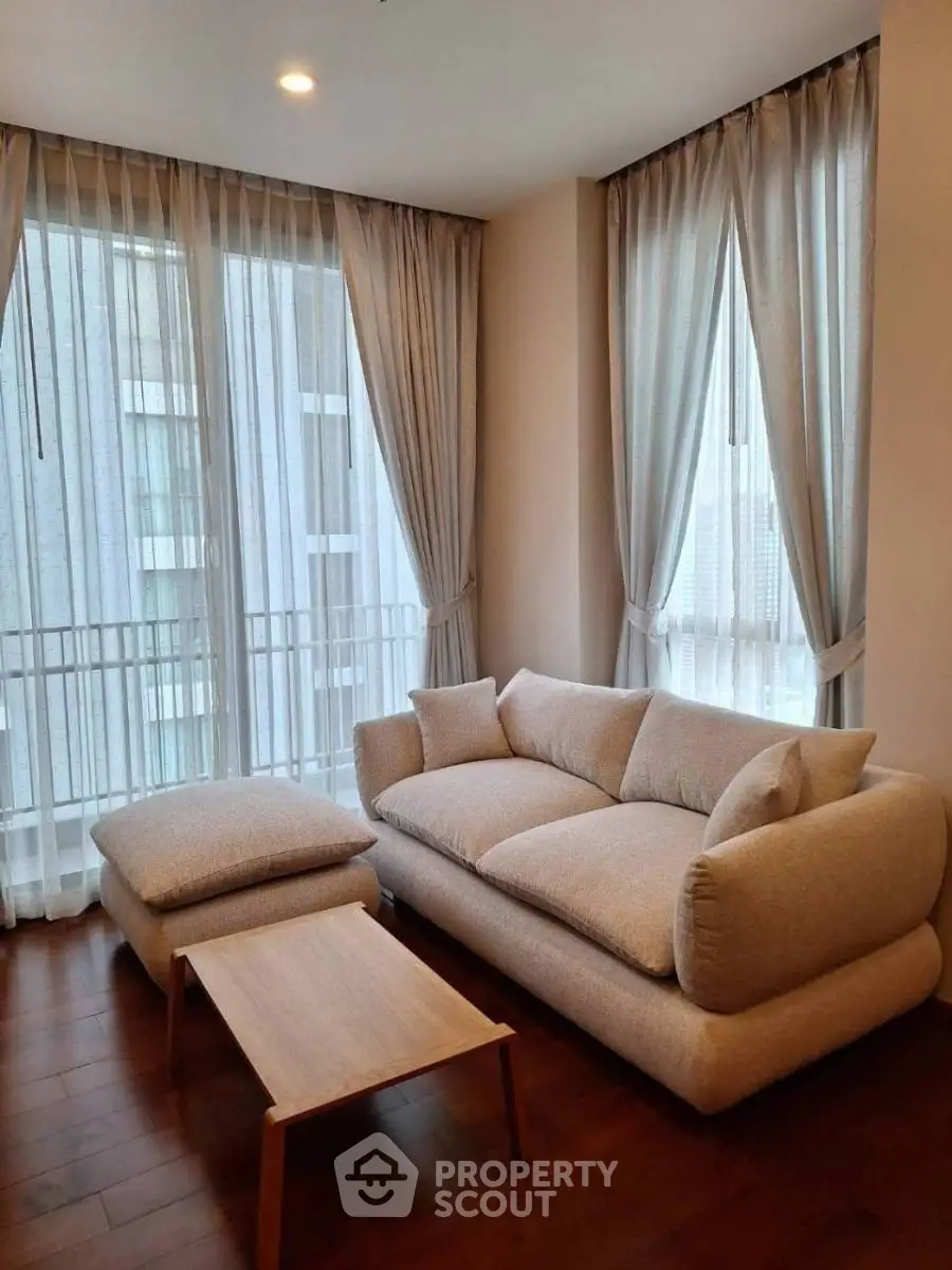 Cozy living room with modern beige sofa and natural light from large windows.