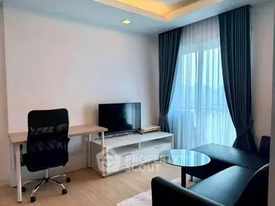 Modern living room with sleek furniture and large window offering natural light.