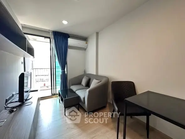 Modern living room with balcony access, featuring sleek furniture and natural light.